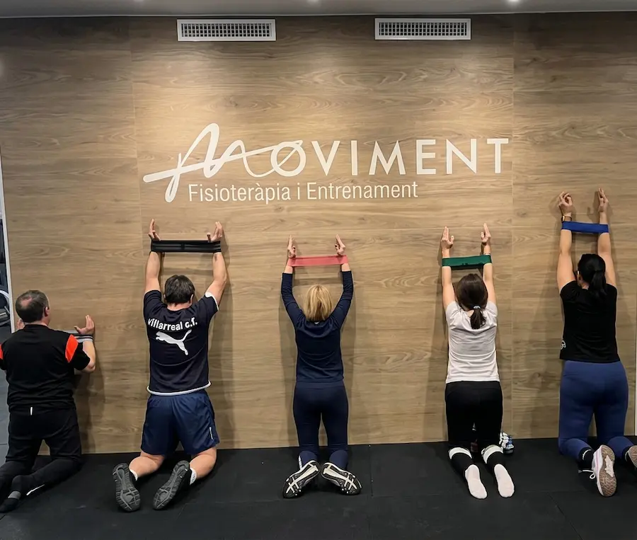 Grupo haciendo estiramientos frente al logotipo de Moviment